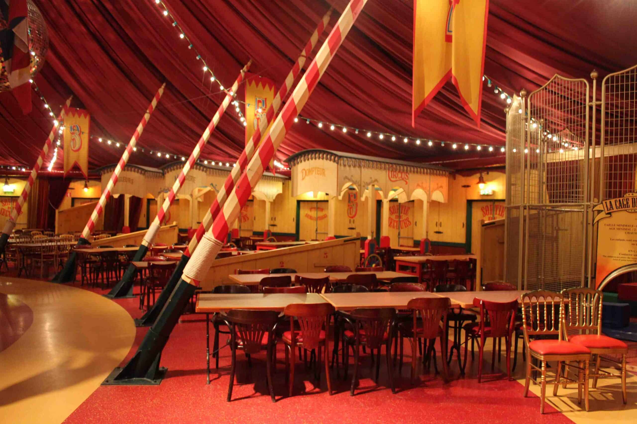 Intérieur d'une tente de cirque avec décorations et sièges rouges.